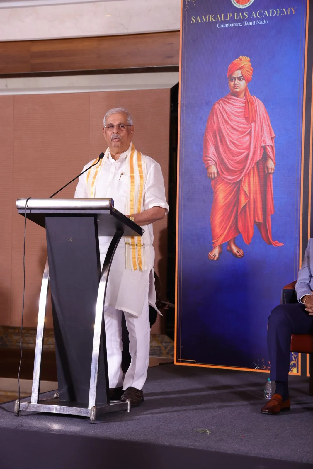 Portrait view of the Chief Guest Honourable Dr. Rajendra Vishwanath Arlekar, Governor of Tamil Nadu, addressing the audience beside the Swami Vivekananda banner.