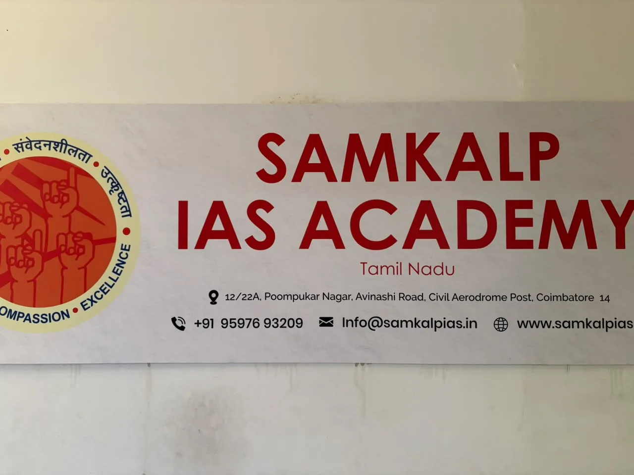 White wall sign reading Samkalp IAS Academy, Tamil Nadu, with the orange academy emblem on the left and the address, phone number, email and website below.
